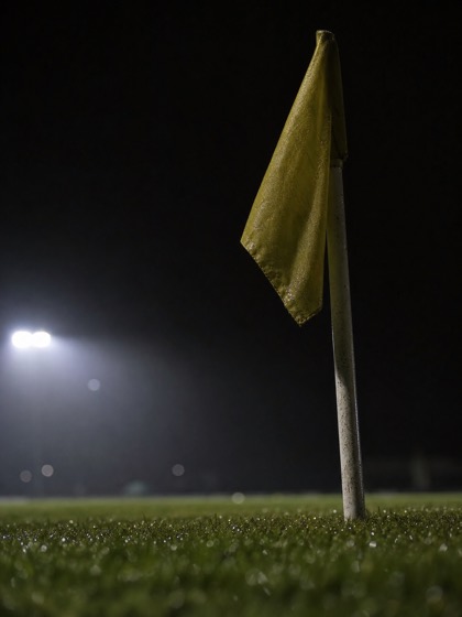 Bandierina del calcio d'angolo su un campo bagnato illuminato dai riflettori di notte